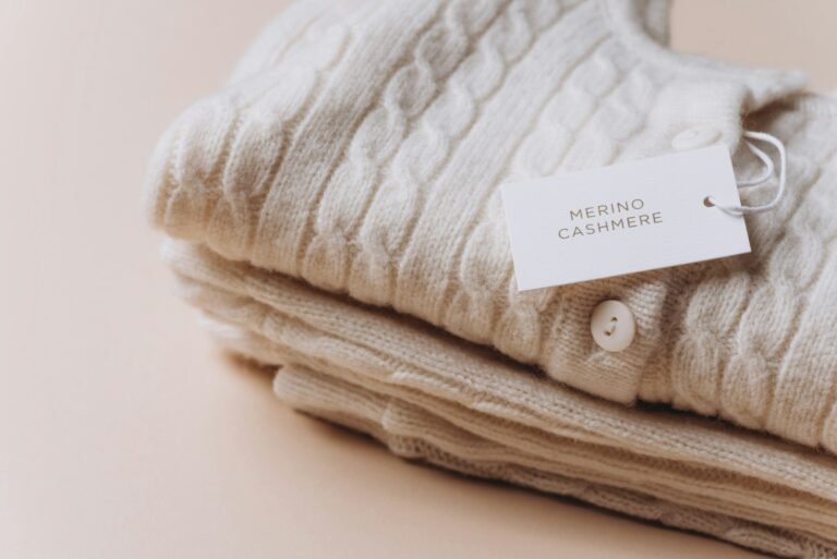 Label with text Merino Cashmere on stack of wool clothes. Tag composition of clothing